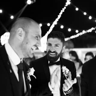Due uomini in abito elegante che sorridono a una festa