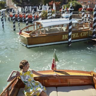 Une femme vêtue d'une robe de soirée jaune prend la pose sur un bateau-taxi à Venise
