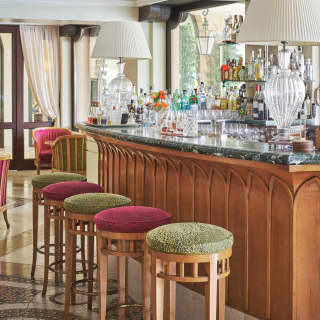 Stylish bar with a green marble countertop with liquor on glass shelves behind