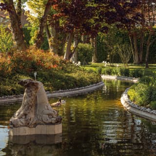 A stone, double-headed animal water feature adds romance and intrigue to the pond in Hotel Cipriani's Casanova Gardens.