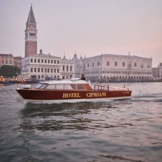 Venetian water taxi emblazoned with 'Hotel Cipriani' sailing by St Mark's square