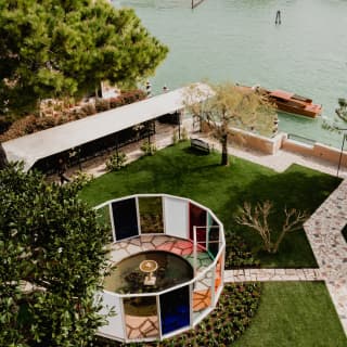 The MITICO structure of tinted panels offers a dreamlike reflection of Venice's hues, seen from above the waterfront gardens.