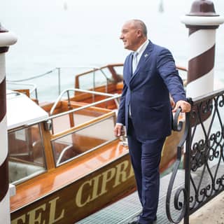 Doorman in a blue suit by a pier outside Belmond Hotel Cipriani