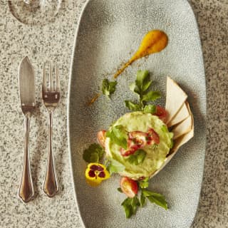 Birds-eye-view of a guacamole starter with melba toast on an oval plate
