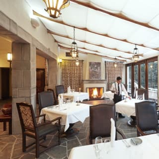 Linen coated restaurant tables on a stone floor under a glass sloped ceiling