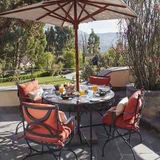 Circular table on an outdoor patio, surrounded by red cushioned chairs