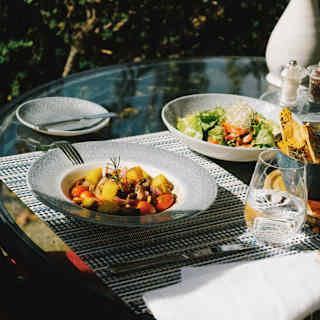Close-up of two vibrant salad dishes served for lunch at a sunny al fresco table on the Curiña Restaurant terrace.
