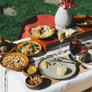 Looking down on plates of nuts, salad, cheese and vegetables served at a low table in the gardens, seen close up.