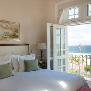 French doors open from a chic bedroom onto a Juliet balcony, with views of Copacabana's iconic beach and Atlantic Ocean