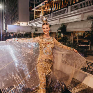 Eine lächelnde Dame in einem goldglänzenden Karnevalskleid 