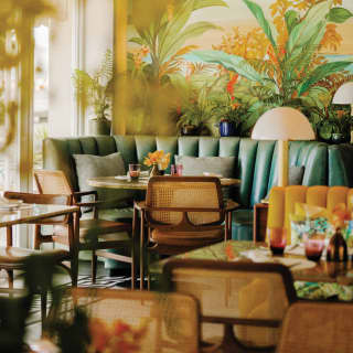 Curving green leather booths, orange table flowers, floral cushions and vibrant wallpaper give this restaurant a tropical vibe