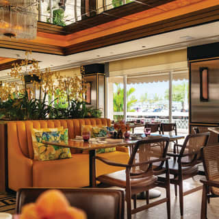 A glass wall offers street-level views of the Copacabana seafront. Tropical cushions adorn orange leather banquettes