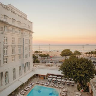 Facade of an art-deco hotel in front of an outdoor pool at sunset