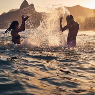 A couple splashing water at Copacabana beach in the sunset