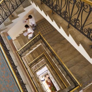 Birds-eye-view of staff descending a stairwell with ornate ironwork railings