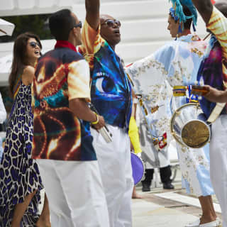 Musicians with guitars, tamborims and timbals dance to their own music poolside as carnival-goers join them and samba