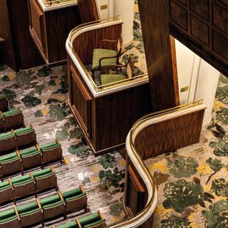 Birds eye view of an art-deco style theatre box with green accent chairs and flooring