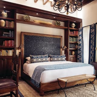 King-size bed surrounded by wooden bookcases in an elegant hotel room