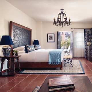 Large hotel room with terracotta floors, ironwork chandelier and blue accents