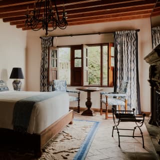 A large bed with a dramatic carved wooden headboard takes centre stage in a bedroom at Casa Limon, rich with wood features.