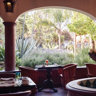 Cloistered restaurant courtyard with tables for two and lush gardens beyond