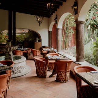 Tiled tables with leather tub chair seating await guests on the colonnaded terracotta terrace of Restaurante del Parque.