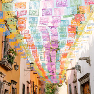Fragile paper bunting, papel picado, flutters above Aldama Street in red, yellow, pink and green to celebrate Dia de Muertos.
.