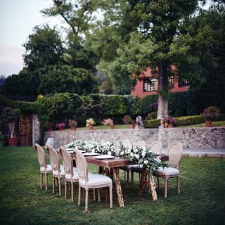 Outdoor banquet table in a garden with a full-length lily centrepiece