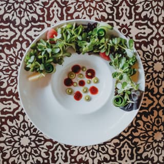Birds-eye-view of a vibrant soup and salad dish against a patterned backdrop