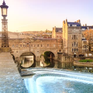 View across a river of Bath city with a stone bridge and a row of Georgian houses