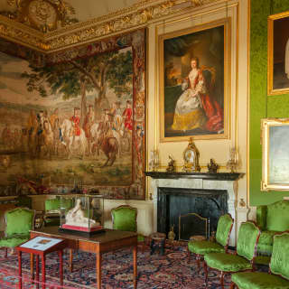 A silk tapestry dominates the Green Drawing Room at Blenheim Palace, which houses portraits and emerald upholstery and walls.