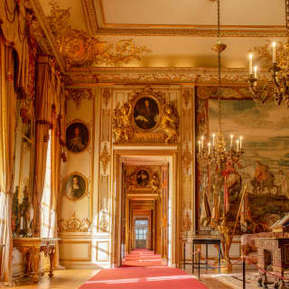 Sun pouring through windows of Blenheim Palace's State Rooms illuminates the gilded frames, chandeliers and ornate cornices.