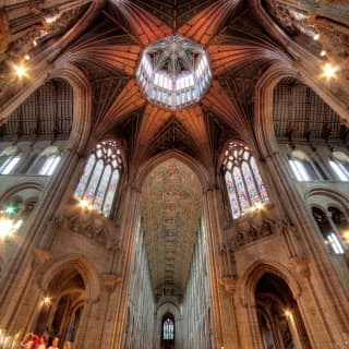 Looking up at Ely Cathedral's Octagon Tower where ceiling arches converge at a medieval panel-painted wood and glass lantern.