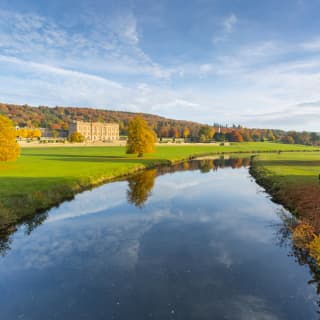 View of Chatsworth House from across manicured lawns and a river
