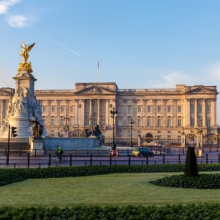 Fountain topped with a gold pegasus in front of Buckingham Palace under blue skies