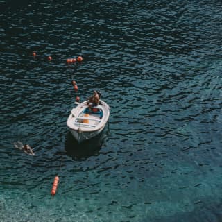 Aerial view of a person swimming in clear water next to a small white boat