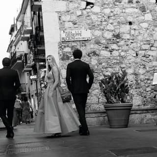 Black and white photo of a dressed up couple walking on the Tormina street