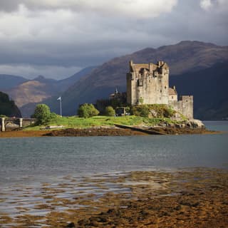 Medieval Scottish castle on an island in a loch surrounded by mountains