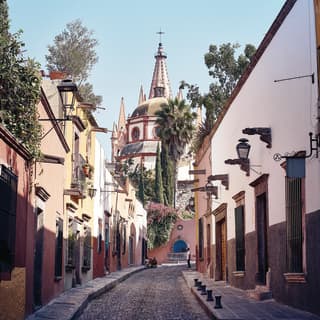 Pastellfarbene Häuser an einer schmalen gepflasterten Straße, die zu einer Kirche führt