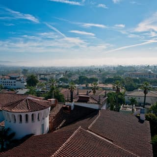 View across the iconic Spanish architecture and terracotta tiled roofs of Santa Barbara to the sea, capped with morning mist.