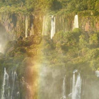 Above a viewing platform, a rainbow shimmers in the spray of thundering cascades that form the spectacle of Iguassu Falls.