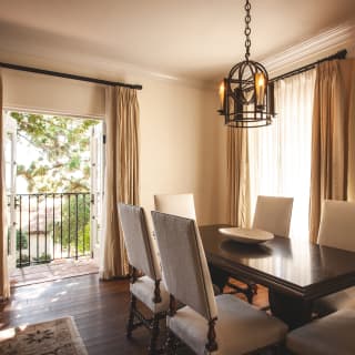 The oak tree suite’s dining table with six high-backed chairs, with doors opening onto the tiled balcony beyond