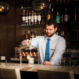 A barman expertly pours a cocktail from a shaker at the elegant El Encanto bar in Santa Barbara