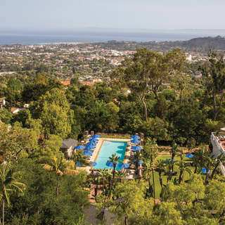 Vista aérea de una piscina de hotel al aire libre entre exuberantes árboles y vegetación