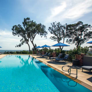 The sparkling water of the zero-edge swimming pool reflects a perfect blue Californian sky with the deep blue ocean beyond