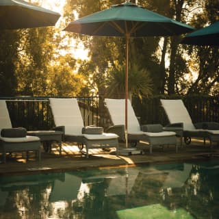 Elegant grey and white loungers under matching blue sunshades line the edge of the hotel pool