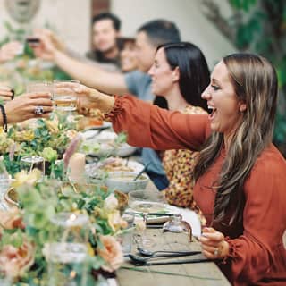 group of people cheering with drinks over the dinner table