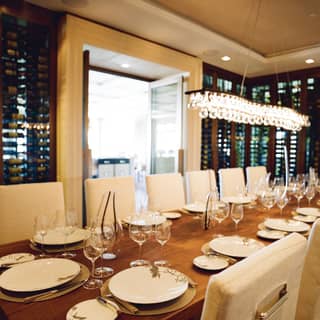 Long table set for private tasting alongside wine racks in the hotel wine room