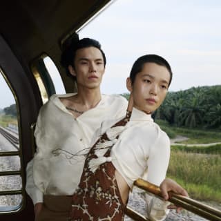 A male and female model lean on the Observation Car rails in a fashion-style image by Kitajima that catches motion and poise.