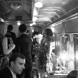 Guests mingling in a bustling bar car on a train